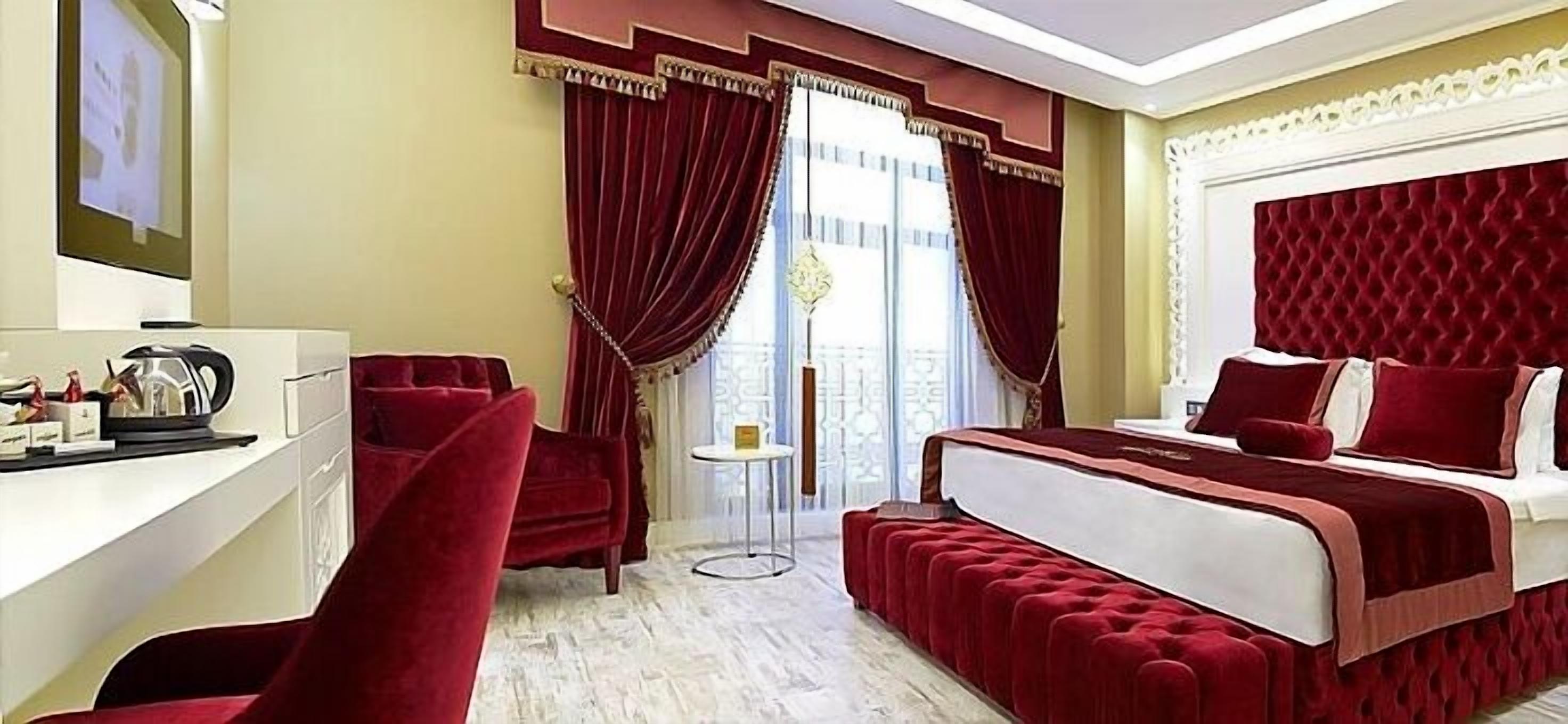 A hotel room with a large bed, a desk with a chair, and a small table.