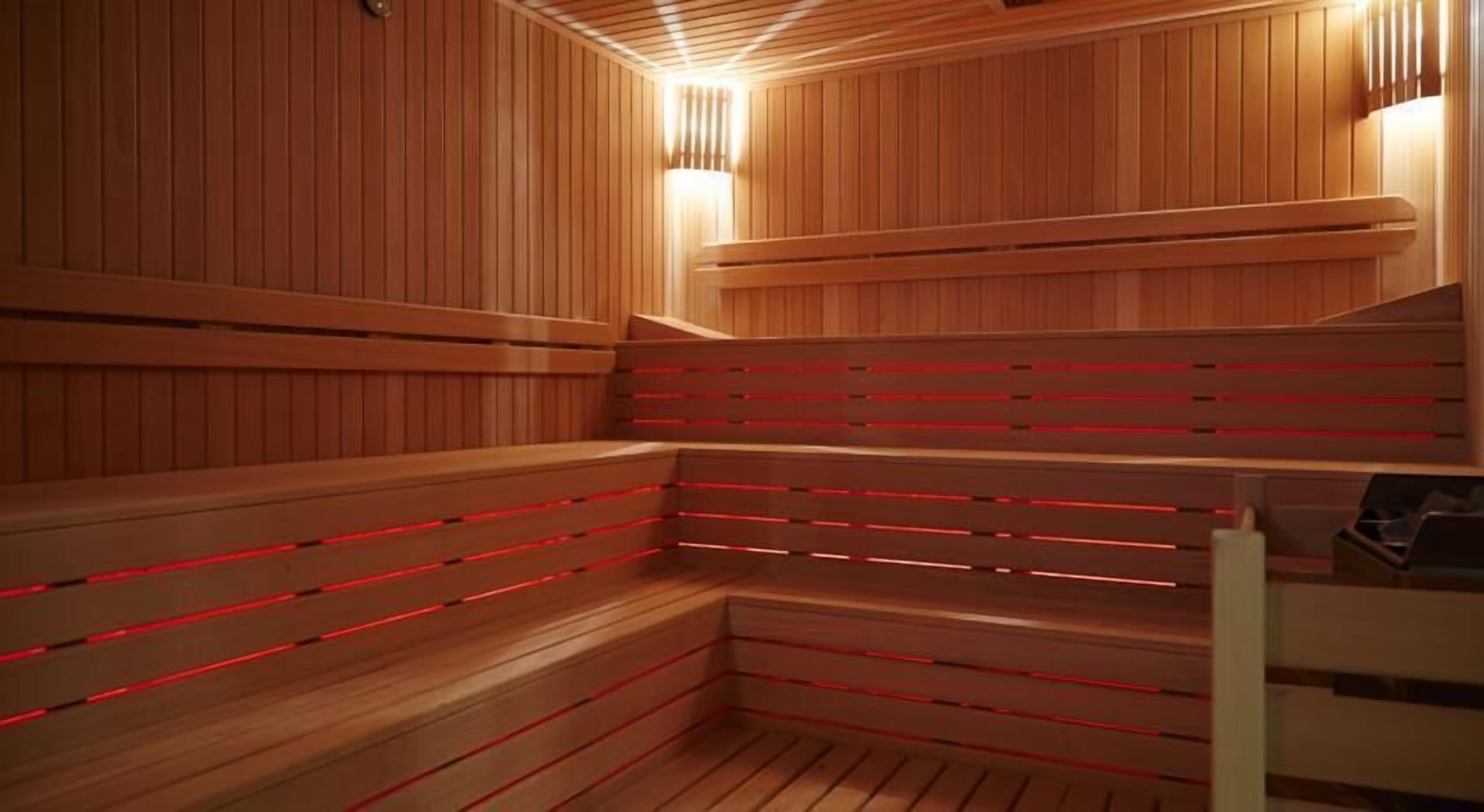 A sauna with wooden benches and red lighting.