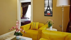 Una habitació amb un sofà groc, un quadre de la Torre Eiffel i una làmpada.