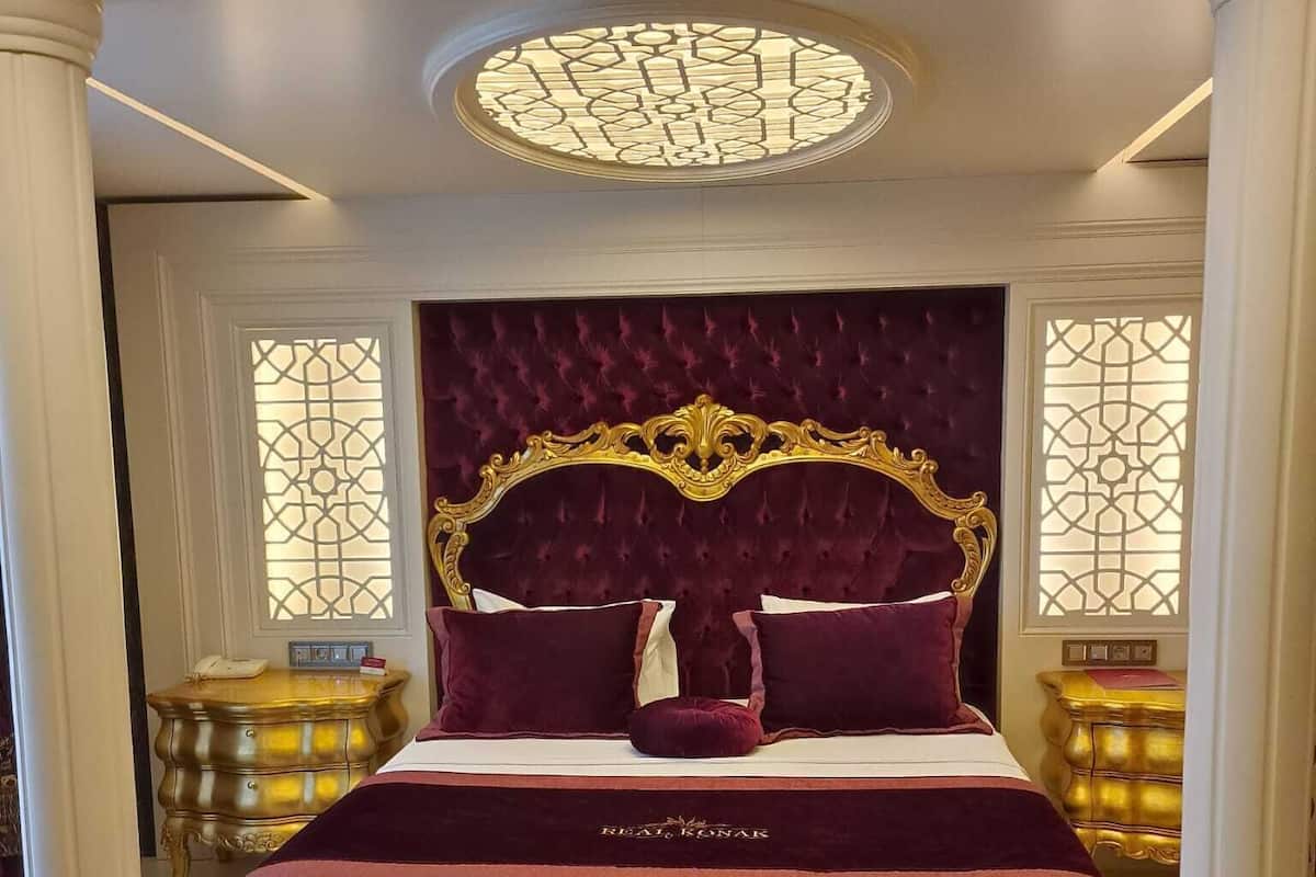 Un dormitorio lujoso con una cama grande, un cabecero ornamentado y una lámpara de techo decorativa.