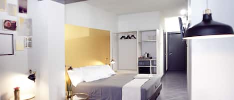 Een moderne hotelkamer met een bed, nachtkastje, lamp en een kleine potplant.