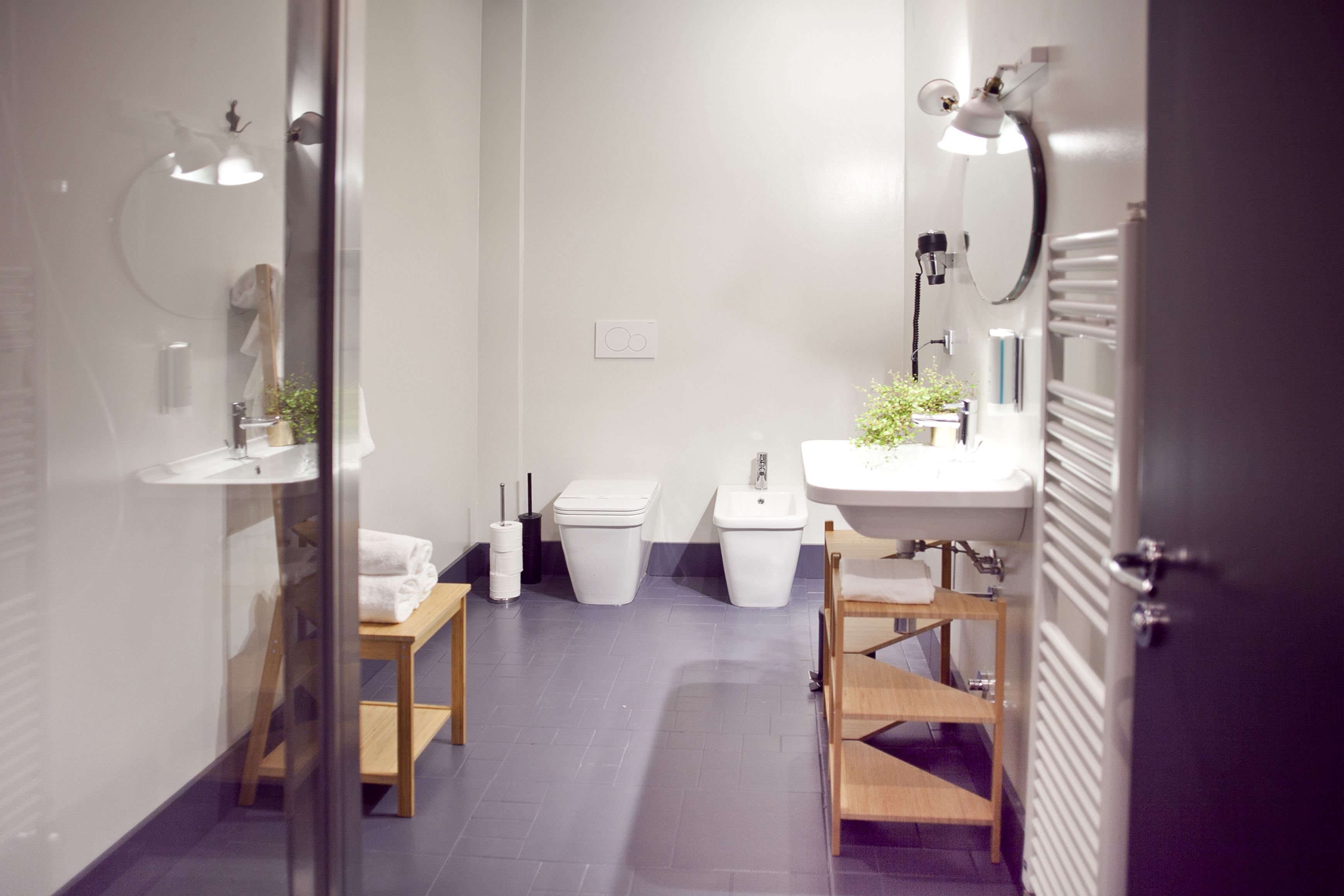 Et moderne badeværelse med glasvæg, vask, toilet og spejl.