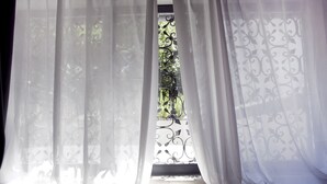 A window with sheer white curtains and a decorative iron grille. - Pepita Lodge (Verona)