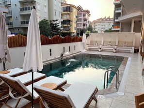 Una piscina al aire libre, sombrillas, tumbonas