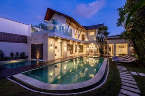 A modern house with a swimming pool, a covered patio, and a well-maintained garden.