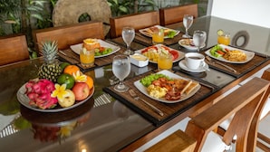 A dining table set with breakfast items, including fruits, eggs, and beverages.