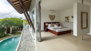 A bedroom with a large bed, a nightstand, and a view of a swimming pool.