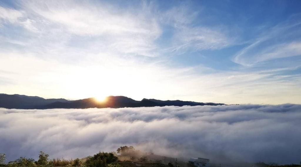 A sunrise over a mountain range with clouds below.