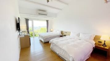 Een hotelkamer met twee bedden, een kroonluchter, een airconditioningapparaat, een nachtkastje met een lamp, en uitzicht op het omliggende landschap.