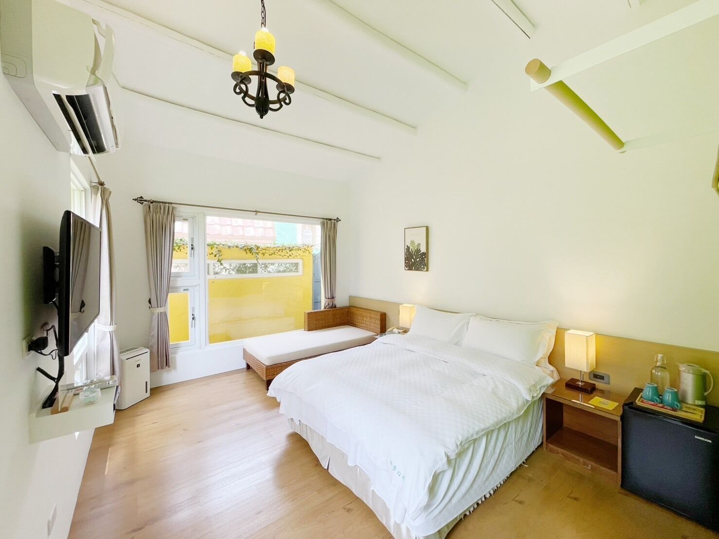Una habitación de hotel con cama, mesita de noche, lámpara y televisor.