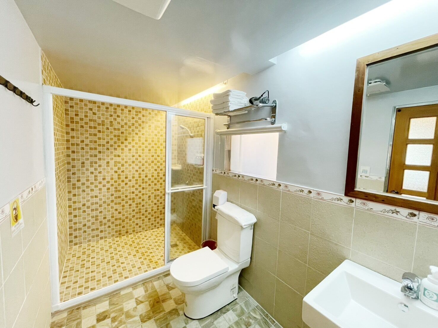A bathroom with a shower, toilet, sink, and a mirror.