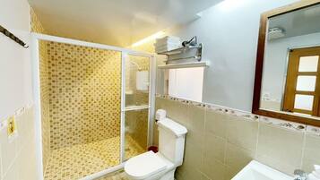 A bathroom with a shower, toilet, sink, and a mirror.