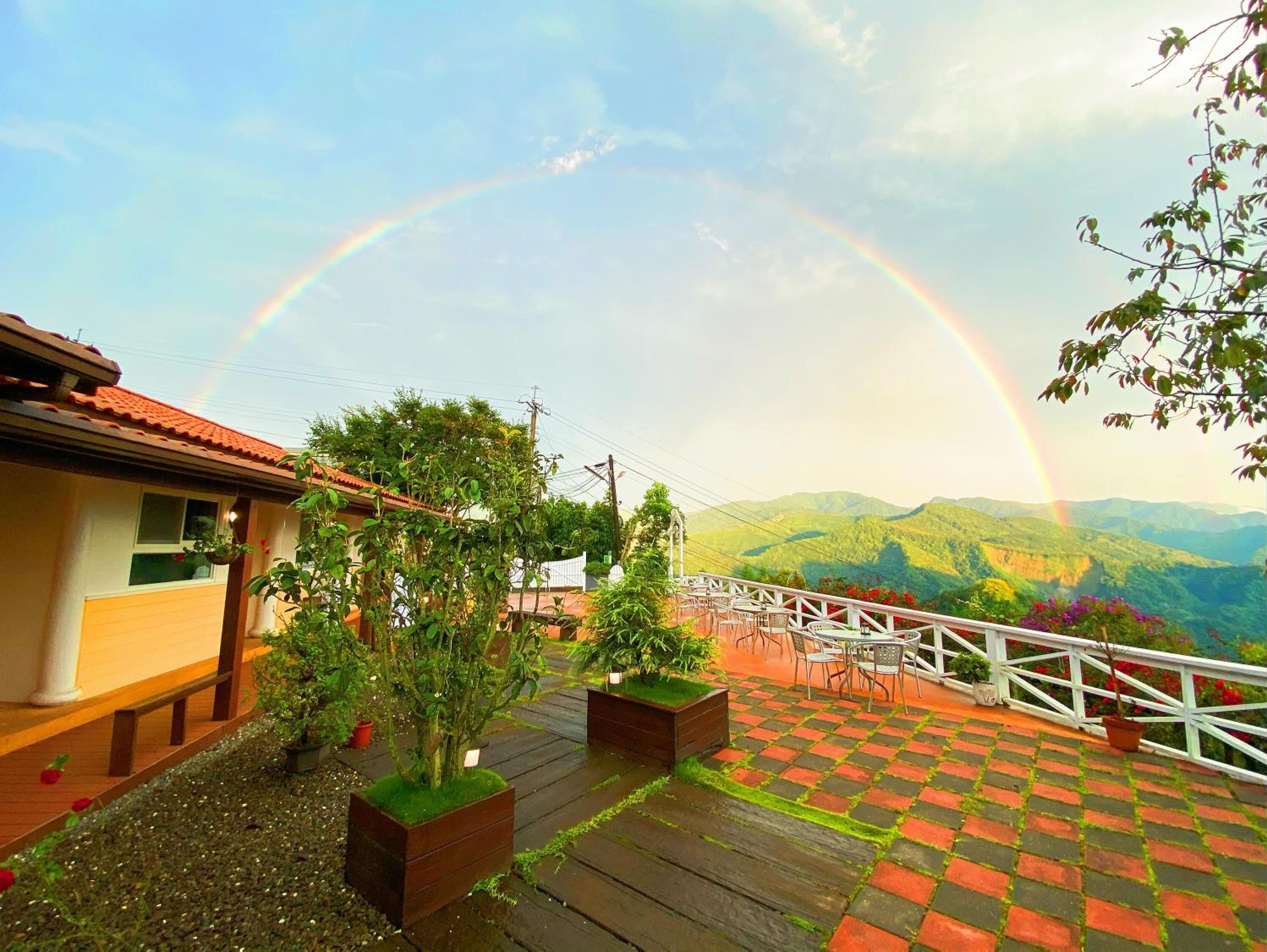 A terrace with a view of mountains and a rainbow.