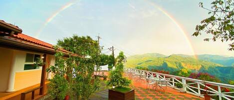 A terrace with a view of mountains and a rainbow.
