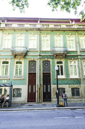 Un bâtiment doté d’une façade verdoyante, de grandes fenêtres et d’une entrée centrale avec une porte décorative.