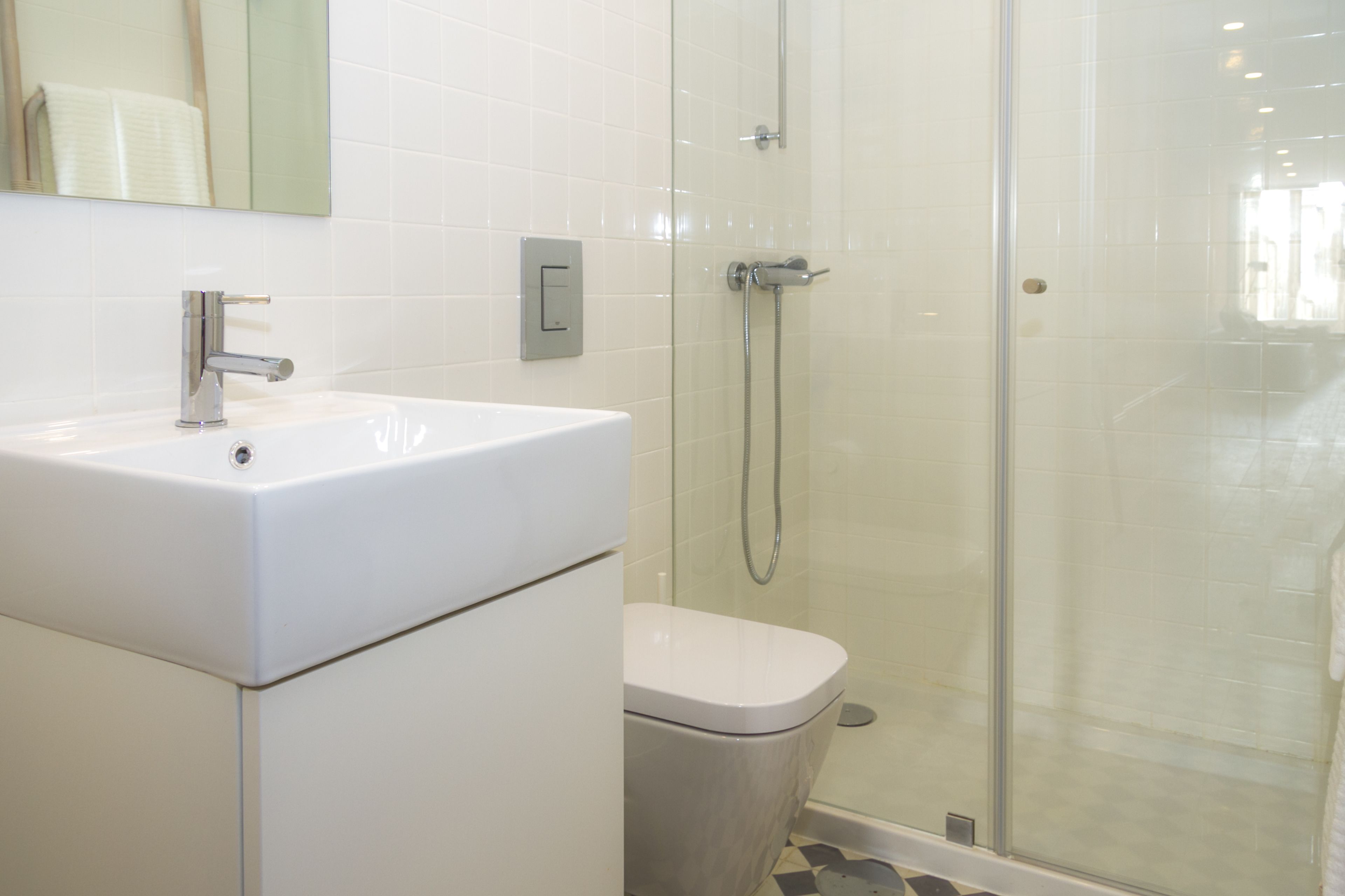 Une salle de bain avec un lavabo blanc, des toilettes et une douche séparée par une paroi de verre.
