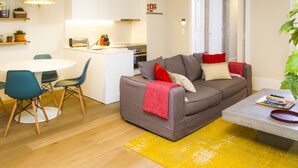 Un salon moderne avec un canapé gris, des fauteuils turquoise et un tapis jaune.