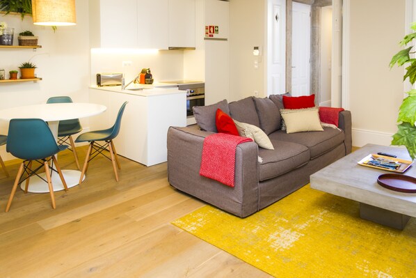 A modern living room with a grey sofa, teal chairs, and a yellow rug. - Liiiving in Porto - Central Garden Flat (Porto)