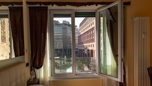 A hotel room with a large window, a bed, a nightstand, and a radiator. - AH - Fashion District (Milan)