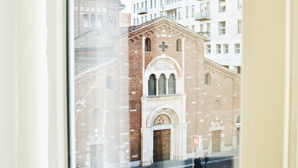 A view of a historic church with a prominent bell tower and arched windows. - AH - Fashion District (Milan)