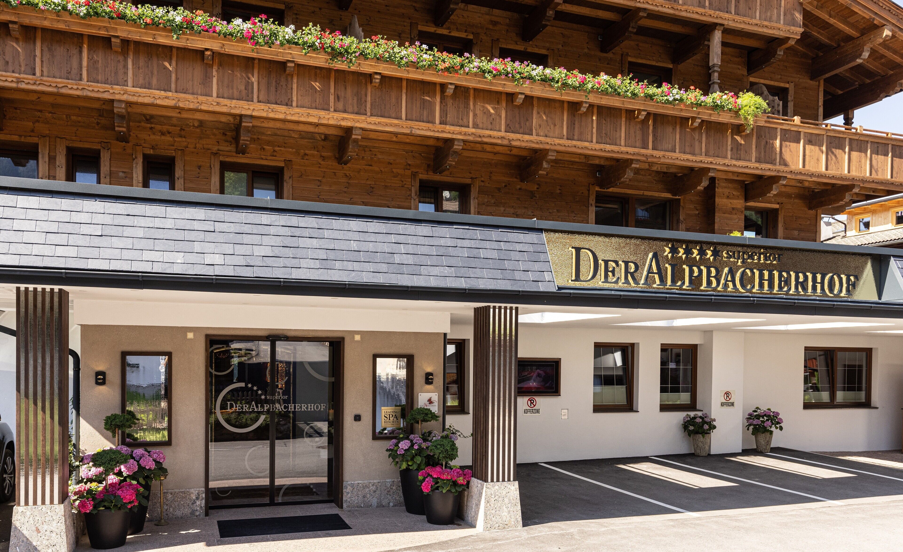 Entrada de un hotel con un letrero que dice 'DerAlpBacherhof'.
