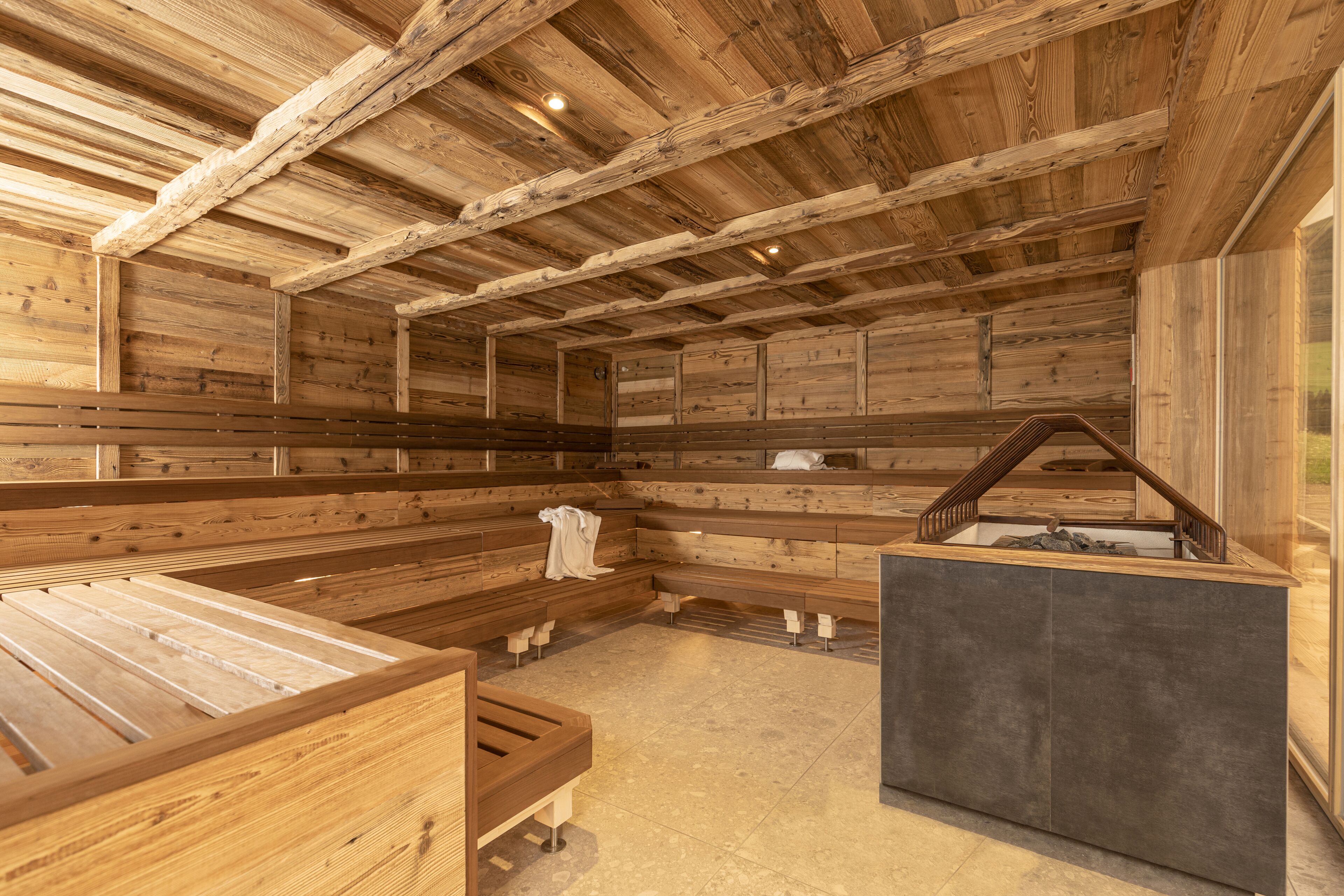 Una sauna con bancos de madera y una plataforma de piedra.