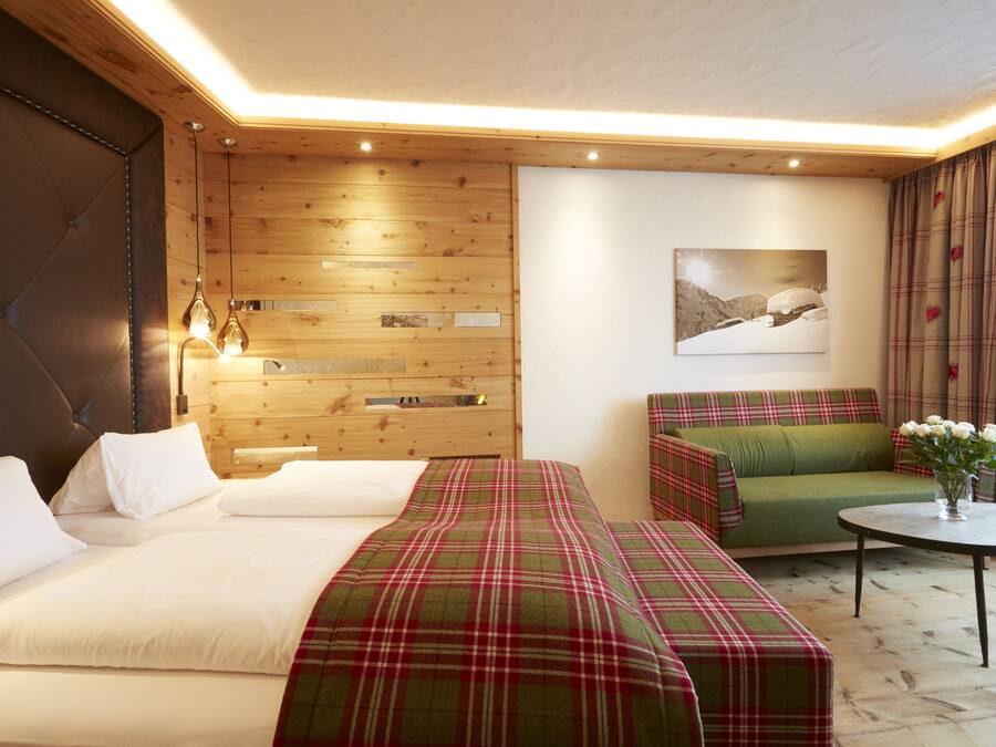 Una habitación de hotel con cama, sofá, una mesita y un panel de pared de madera.