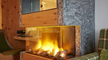 Un interior moderno con una chimenea de vidrio, paneles de madera y una butaca estampada de tartán.