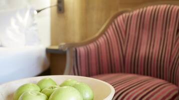 Un bol de manzanas verdes sobre una mesa de madera junto a una silla a rayas.