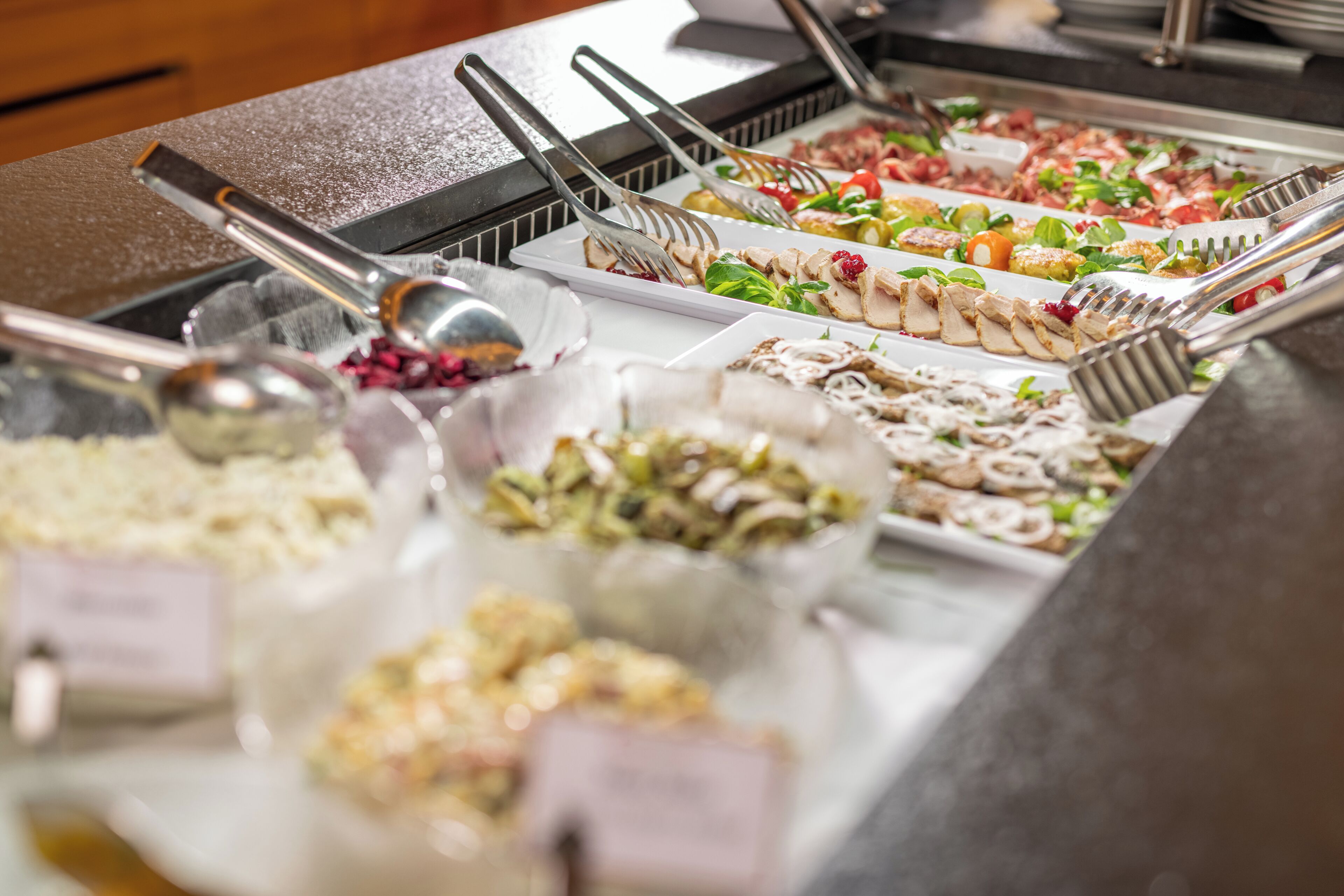 Un bufé con diversas opciones de comida, incluyendo ensaladas, carnes y postres.