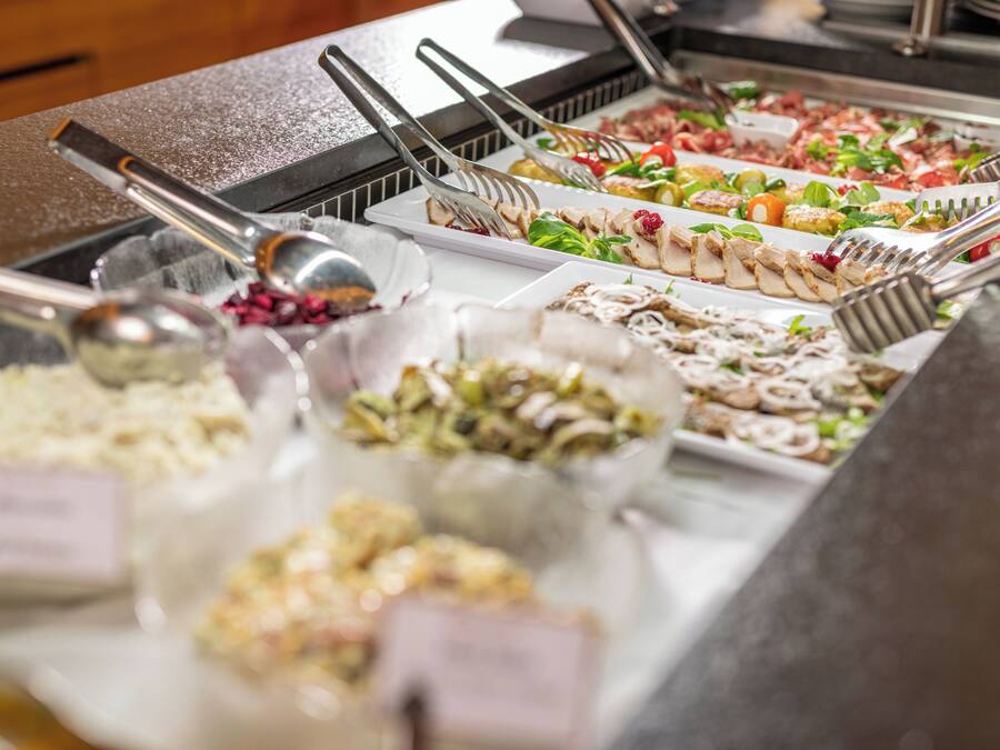 Un bufé con diversas opciones de comida, incluyendo ensaladas, carnes y postres.