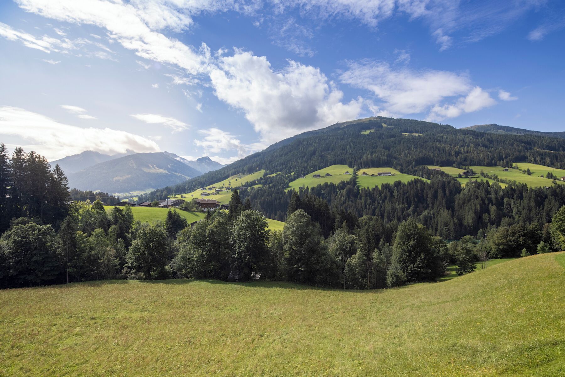 A mountainous landscape with green fields and scattered buildings.