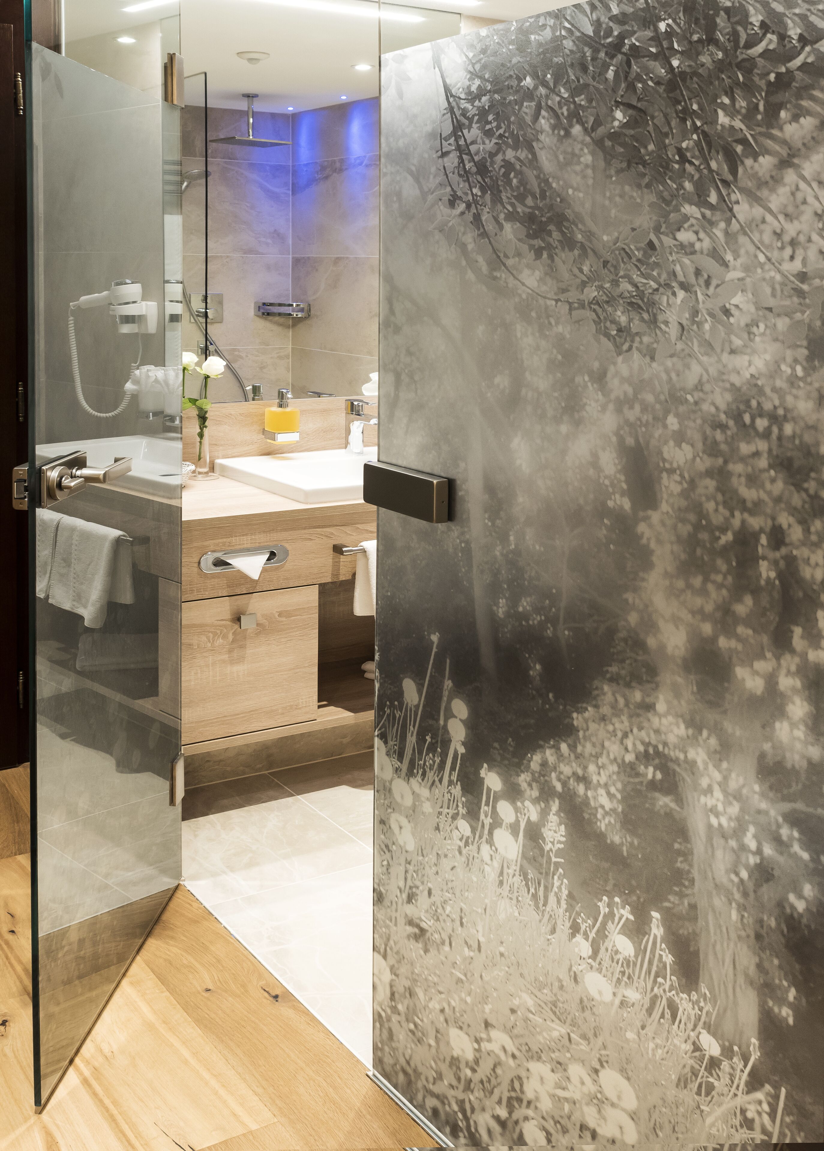 Ein modernes Badezimmer mit Duschkabine aus Glas, einem Holzwaschtisch und einem großen Spiegel.
