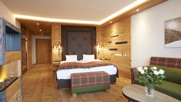 A modern bedroom with a wooden floor, a bed with plaid bedding, a green sofa, and a vase with flowers.