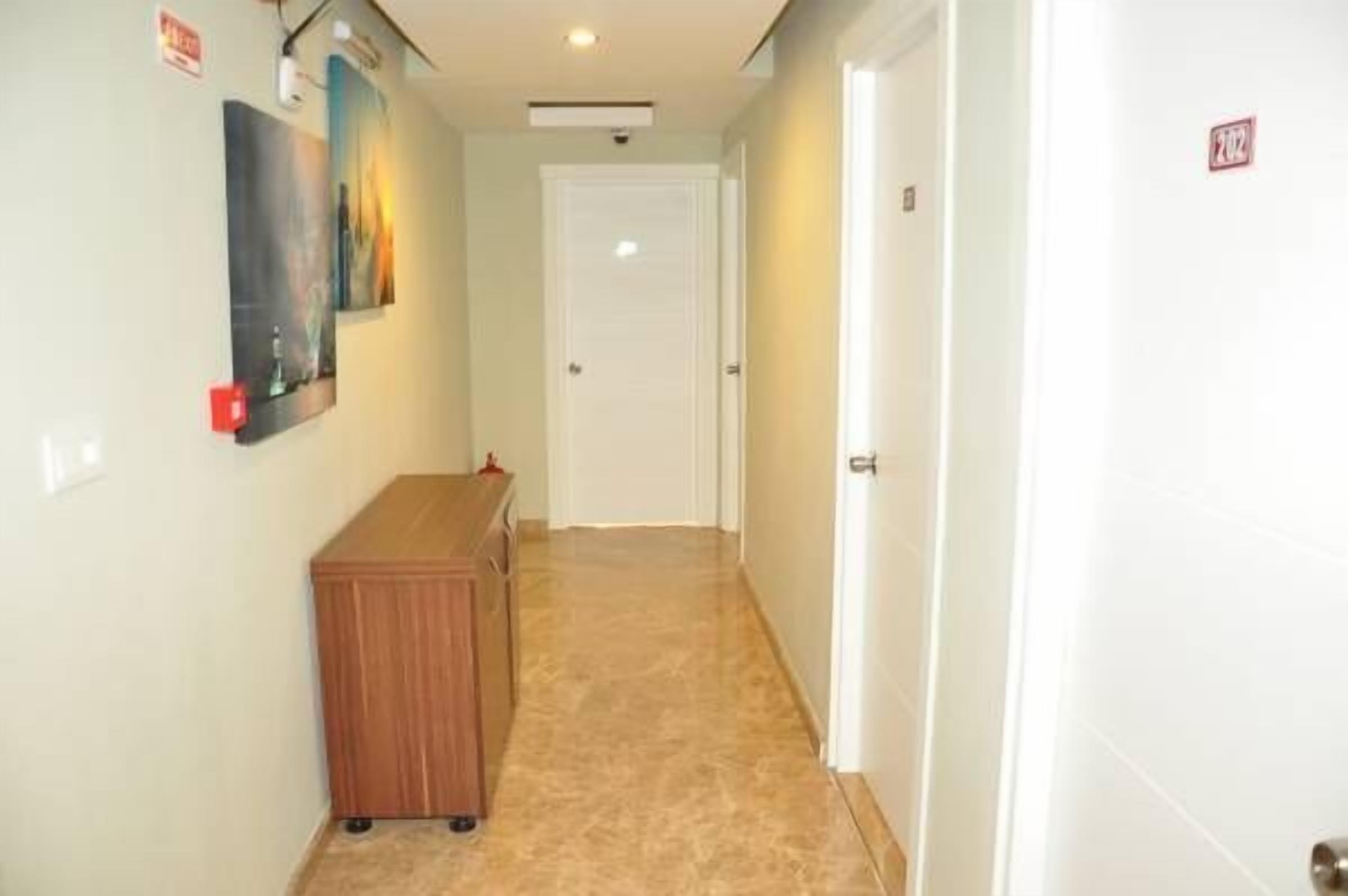 A narrow hallway with a wooden bench, a door at the end, and a wall-mounted light fixture.