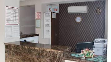 Un área de recepción con mostrador de mármol, un reloj y un aire acondicionado instalado en la pared.