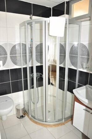 A corner bathroom with a glass-enclosed shower, a white sink, and a toilet. - River Boutique Hotel (Manavgat)