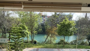 Habitación con sofá y sillones orientados a una ventana con vistas a un lago y vegetación.
