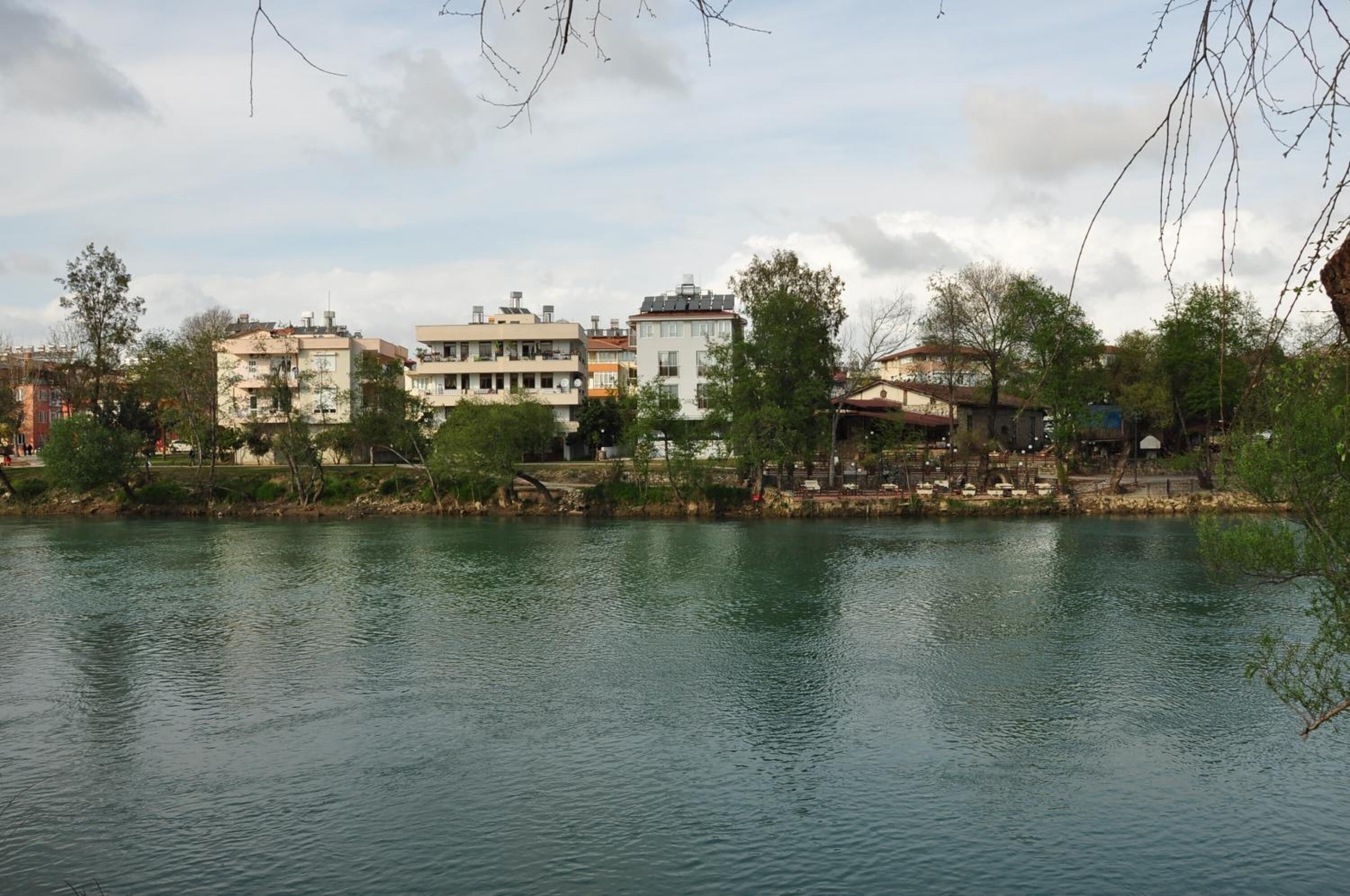 A calm lake with buildings in the background.