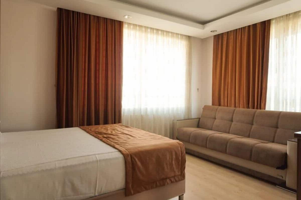 Una habitación de hotel con cama, sofá y cortinas.