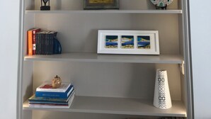 Una estantería con objetos decorativos, incluyendo un plato, cristalería, un cuadro enmarcado y libros.