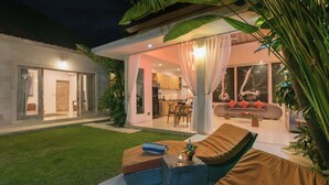 Un espacio exterior moderno con sofá, cojines y una mesita con una vela.