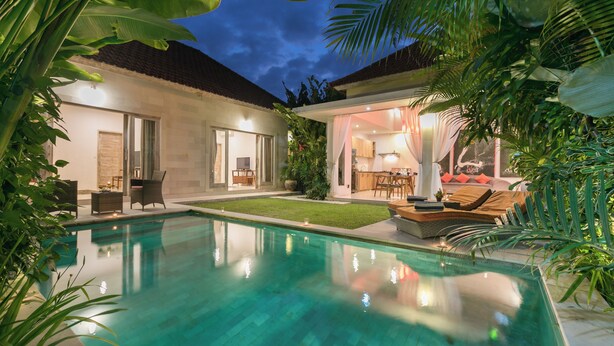 Una casa moderna con piscina, un patio con mobiliario exterior y un interior bien iluminado.