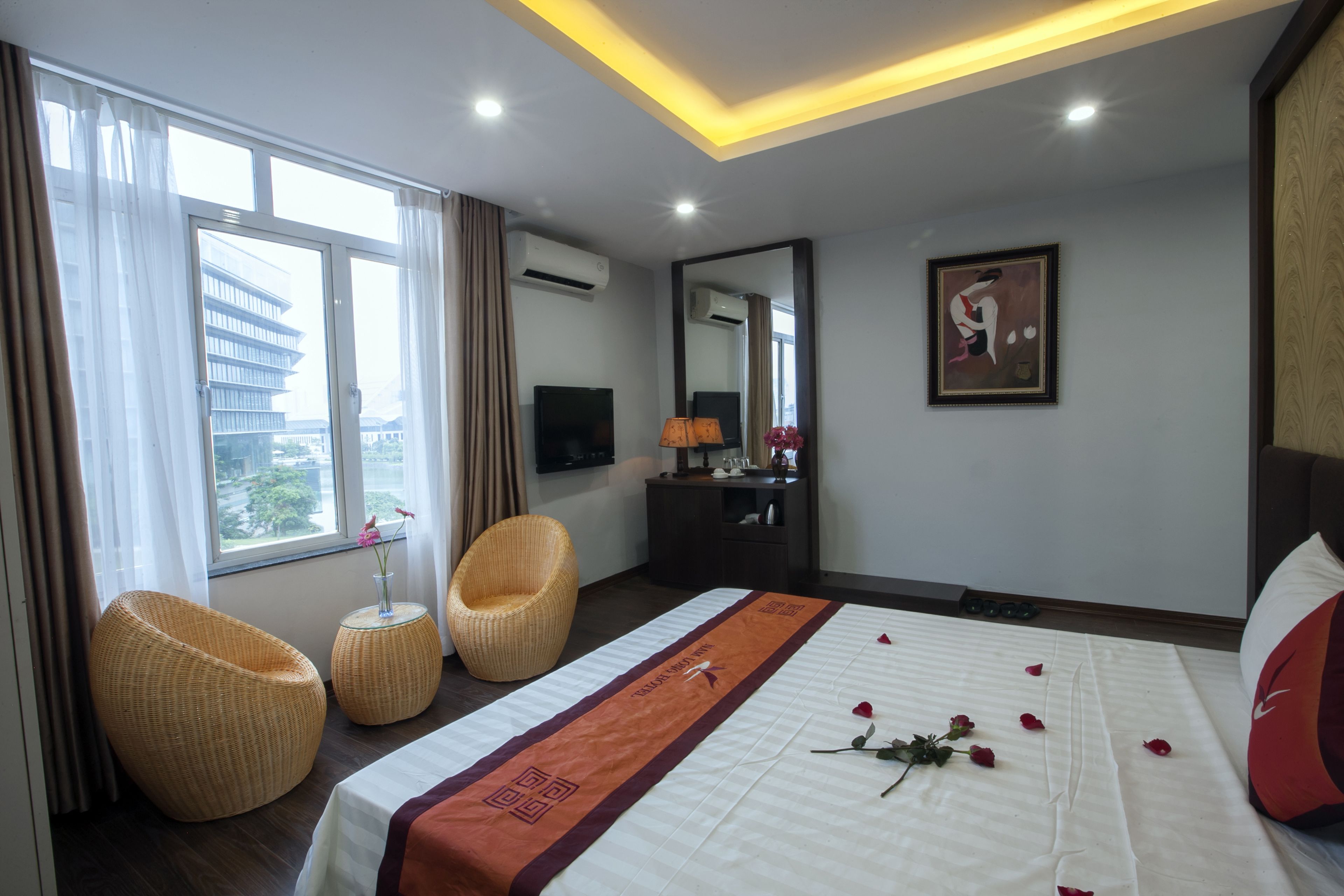 A hotel room with a bed, a chair, a desk, a TV, and a window with curtains.