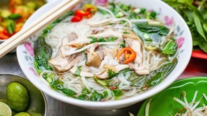 A bowl of noodle soup with various toppings and a pair of chopsticks resting on the side. - Nam Long Hotel Ha Noi (Hanoi)