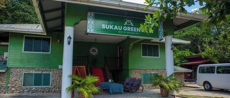 Un edificio con fachada verde y un letrero que dice "SUKAU GREEN BED & BREAKFAST".