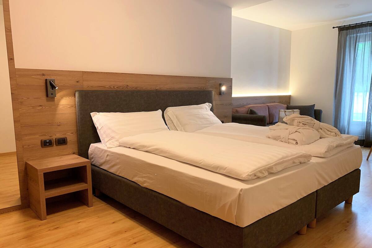 A modern bedroom with a wooden headboard, a bedside table, and a large bed with white bedding.