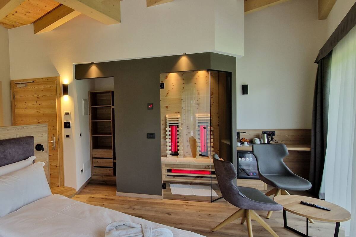 A modern hotel room with a large bed, a desk, and a massage chair.