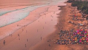 An aerial view of a beach with people walking along the shore and umbrellas set up on the sand. - Villa Pacha seminyak by Best deals Asia Hospitality (Seminyak)