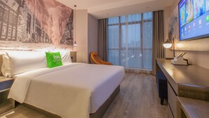 A hotel room with a large bed, a desk, a television, and a cityscape mural on the wall. - ibis Styles Wuhan Optics Valley Square Hotel (Wuhan)